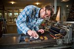 Anthony Olson cleans a press before preparing to print. Photo: davebrewerphoto.com