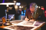Photographer Frank Bennet is titling, signing and dating his prints on display in-between talking to attendees. Photo: Garrett Allen
