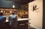 Two patrons sit at the bar and enjoy some food next to one of Dan Christofferson's paintings. Photo: Talyn Sherer