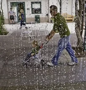 Man wearing green polo shirt pushes a kid in a stroller.