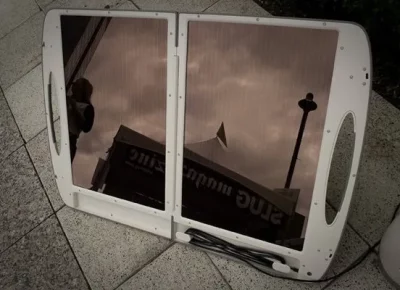 Portable solar panel with the Slug Magazine event sponsor booth in its reflection.