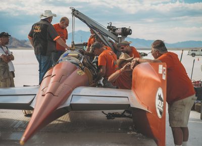 Most people racing are seeking out records within specific criteria. There are different classes based upon body category, engine size, aerodynamic modifications (supercharged or not), fuel or gas. This vehicle wears “AA/BGS” on its side, which means it’s a Blown Gas Streamliner with an engine above 500 ci.