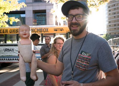 Smiles all around as Logan Whitmore, co-owner of Copperhive Vintage in Sugarhouse, showed off one of his antique dolls, “High Five.” Photo: JoSavagePhotography.com