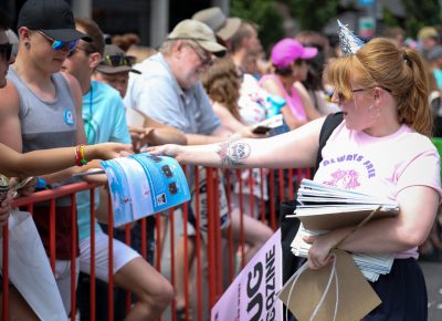 Vreni Romang passes out copies of SLUG Magazine as she marches in the Pride Parade. Photo: John Barkiple.