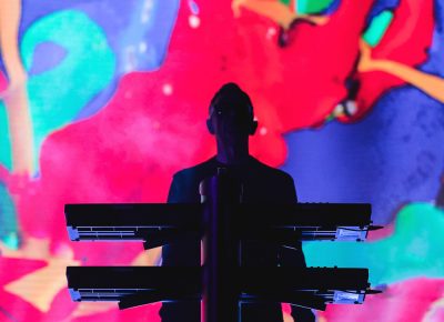 Colorful backgrounds cover the screen as tall as the venue with Andy Fletcher standing at the keyboard. Photo: Lmsorenson.net