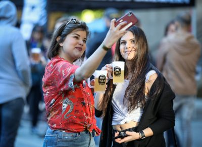 (L–R) Esther and Ash pause for a selfie as they start their Brewstillery tour with Red Rock’s Blackbier. “I like it. It’s not so bitter…on the lighter end,” Esther said. The Craft Lake City pretzel necklace project also made them smile. Photo: John Barkiple