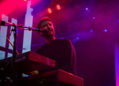 The keyboardist bathed in colorful stage light.