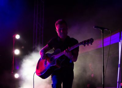 Dramatic stage light plays with guitarist.