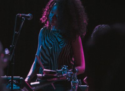 Felicia banging out some aux percussion under a flood of light. Photo: Matthew Hunter