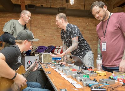 (L–R) Shea Sterner (second from right) and Mark Wursten (right) from Transmutation Devices brought a large selection of effects pedals to SLAMM. Their “Candlelight” pedal is similar to a “Range Master,” but it distorts more than just treble. They offer many pedal flavors in boosts, overdrives, fuzzes, distortions, delays and pre-amps. And with maker flair, they also etch their own boxes and operate from Sterner’s basement and Wursten’s kitchen.