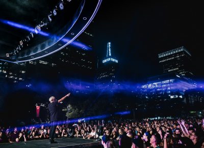 Downtown is pumping with the beats from Robert DeLong, concert goers of the Twilight Concert Series are packed in the Gallivan Center in downtown SLC with the nearby Walker Center in frame.