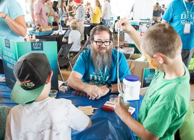 Craft Lake City STEM Craft Assistant Peter Reed helps pint-sized inventors stir up cup-sized portions of DIY slime.