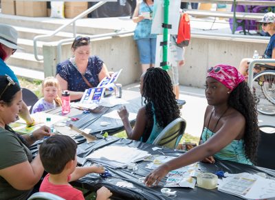 Craft Lake City Kid Row Volunteers help kids (and parents) build cardboard masks from recycled materials. At the next station, kids painted their masks.