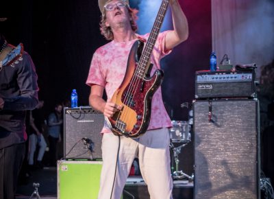 Brendan Canning lifts his guitar in the bright stage lights.