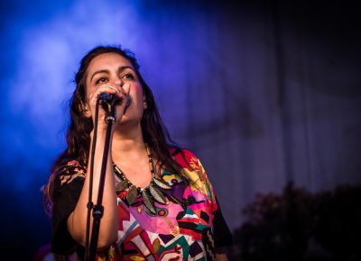 Ariel Engle sings in the bright stage light of blues and purples.