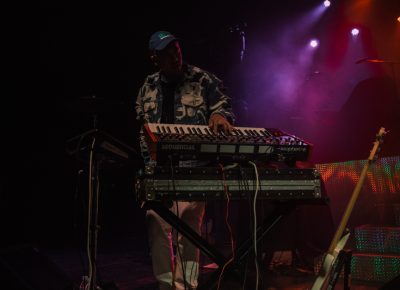 Twin Shadow instrumentalist mashing keys with bass guitar on standby.