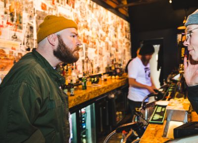 Over the loud tones of the music, a patron asks for another round at the bar.