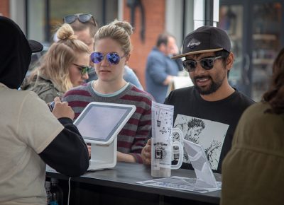 (L-R) Lily Godfrey and Wafiq Ali stock up on tokens as they grab their plastic steins at the entrance of Brewstillery at Trolley Square. They look forward to drinking beer in this nice weather. Photo: John Barkiple