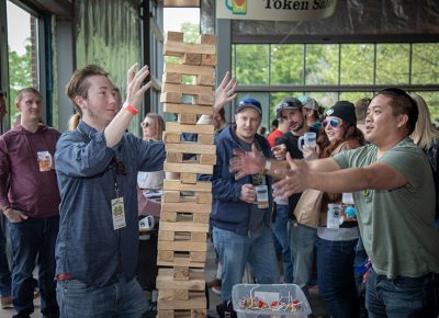 (L-R) Kayden Corbett and Van Nguyen get into some Jenga while the crowd cheers them on at the Brewstillery main space entrance. Photo: John Barkiple