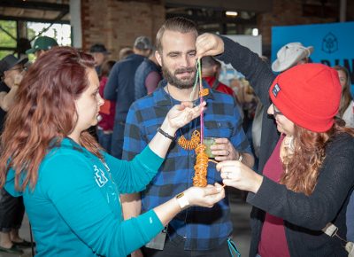 (L-R) Briana Dalton with Chelley and Joe Coleman get their beer craft on at the Yelp pretzel table. “I make the best necklaces,” Joe said. Photo: John Barkiple