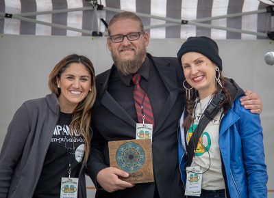 Ana Valdemoros and Angela H. Brown rewarding Holystone Distilling co-owner and distiller Ethan Miller with the People's Choice: Best Brewstillery Cocktail and Singular Contribution to Utah Spirits Awards. Photo: John Barkiple