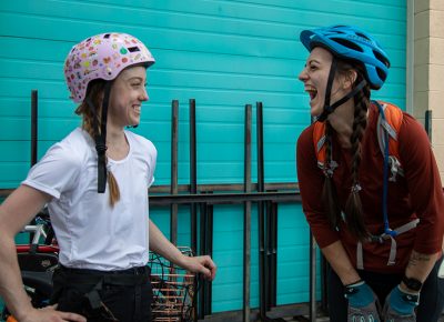 (L–R) Renée Draper and Marian Lewis share a pre-race joke. First time alley-cater and first-place finisher Draper heard about the race from her work pal, Scott Morely. That the alley cat is like a scavenger hunt appeals to her game-loving personality. Third-place finisher Lewis rode a rental in SLUG Cat 2019. She joined the race today because she loves the social aspect of a good bike gathering. Photo: Kaylynn Gonazlez