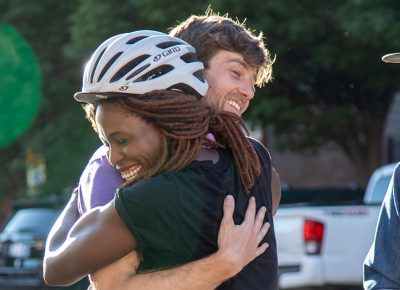 (L–R) Nkenna Onwuzuruoha hugs Davey Davis. She mis-mapped her manifest, so she didn’t reach the podium, but she still finished with a smile. Davis handicapped himself in today’s race by riding SLUG’s old beater bike. Photo: Kaylynn Gonazlez