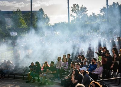 An expectant crowd waits in a haze of fog.