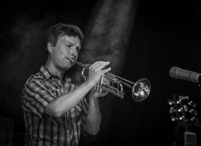 A ray of light falls on Dave Jorgensen, trumpeter for Blind Pilot, as he blasts on his horn!