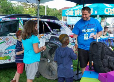 The Subaru booth handing out photos of children by their car.