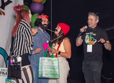 (L–R) Drea Bedke awards Matt Arellano as Cheech and Lashena Stevens as Chong third place in the Boo!stillery costume contest as John Ford narrates the action.