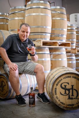 Head Distiller James Fowler sits with some of Sugar House Distillery's barrels.