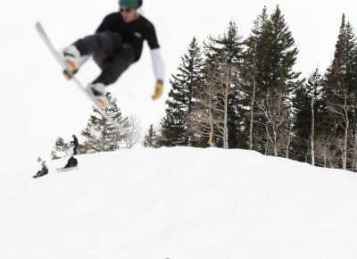 Onlookers take in all the jumps and tricks as a snowboarder passes over with an ollie and heel side grab at the SLUG 20th Anniversary Meltdown Games at Brighton Resort.