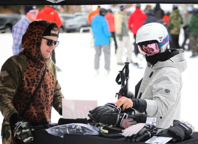 Skier coming down the hill at Brighton stops to pick up some Hand Out Gloves at Sponsor Village at the SLUG 20th Anniversary Meltdown Games at Brighton Resort.