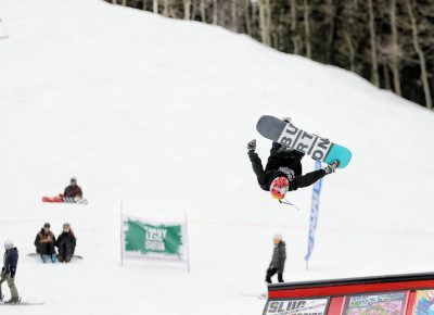 Snowboarder in the air during a flip off the jump at the SLUG 20th Anniversary Meltdown Games at Brighton Resort.