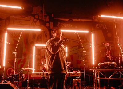 Ben Ra performs against the backdrop of flashing neon lights.