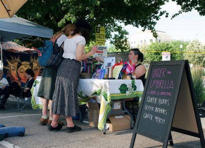 Attendees visiting the booth by Under the Umbrella Bookstore.