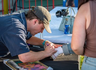 Ritt Momney signs a fan's Converse kicks.