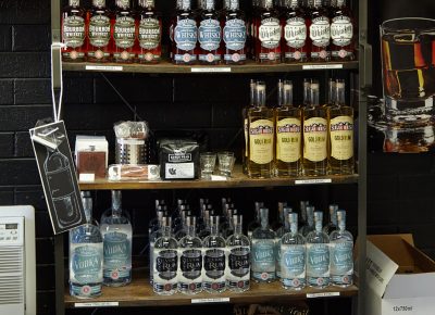 A shelf display of the available liquors and some merch items for sale.