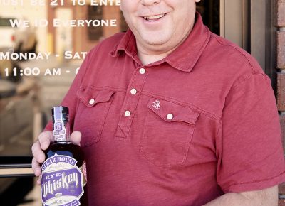 Owner and Master Distiller James Fowler poses in front of the distillery doors with a bottle of the new Barrel Master #2 Rye Whiskey.