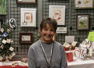 Barb Oxborrow gleams next to her holiday portraits.