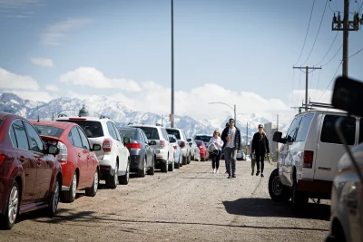 People walking between lines of parked cars to get to the Bunny Hop entrance.