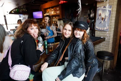 Three friends posing at the bar together.