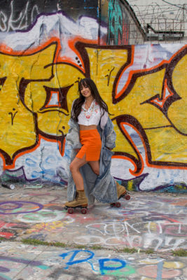 Cintia Lastra wearing an orange skirt while skating on roller skates.