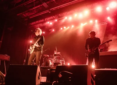 Spoon playing live on a stage with red lighting.