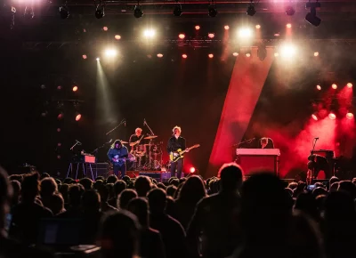 Spoon playing music live on stage with red lighting.