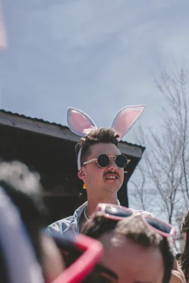 Picture shows the tops of some attendees heads. Above them, is a person with round sunglasses and bunny ears on.