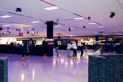 A group of people are on a roller skating rink at Neptune Skating. They're illuminated by a black light. Photo: Lexi Kiedaisch