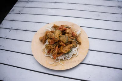 Chicken pad thai on wood plate.