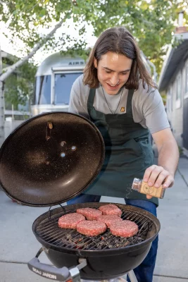 Chris Smith seasons burgers on the grill with a Salt Smith blend.